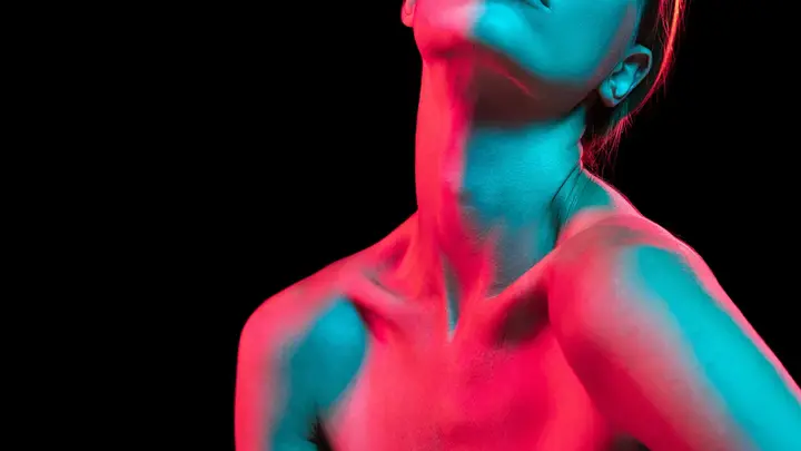 A womans neck and chest illuminated by red and green